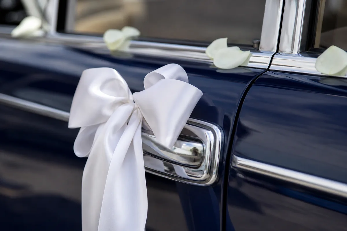 Ruban de satin blanc noué sur une poignée de porte chromée