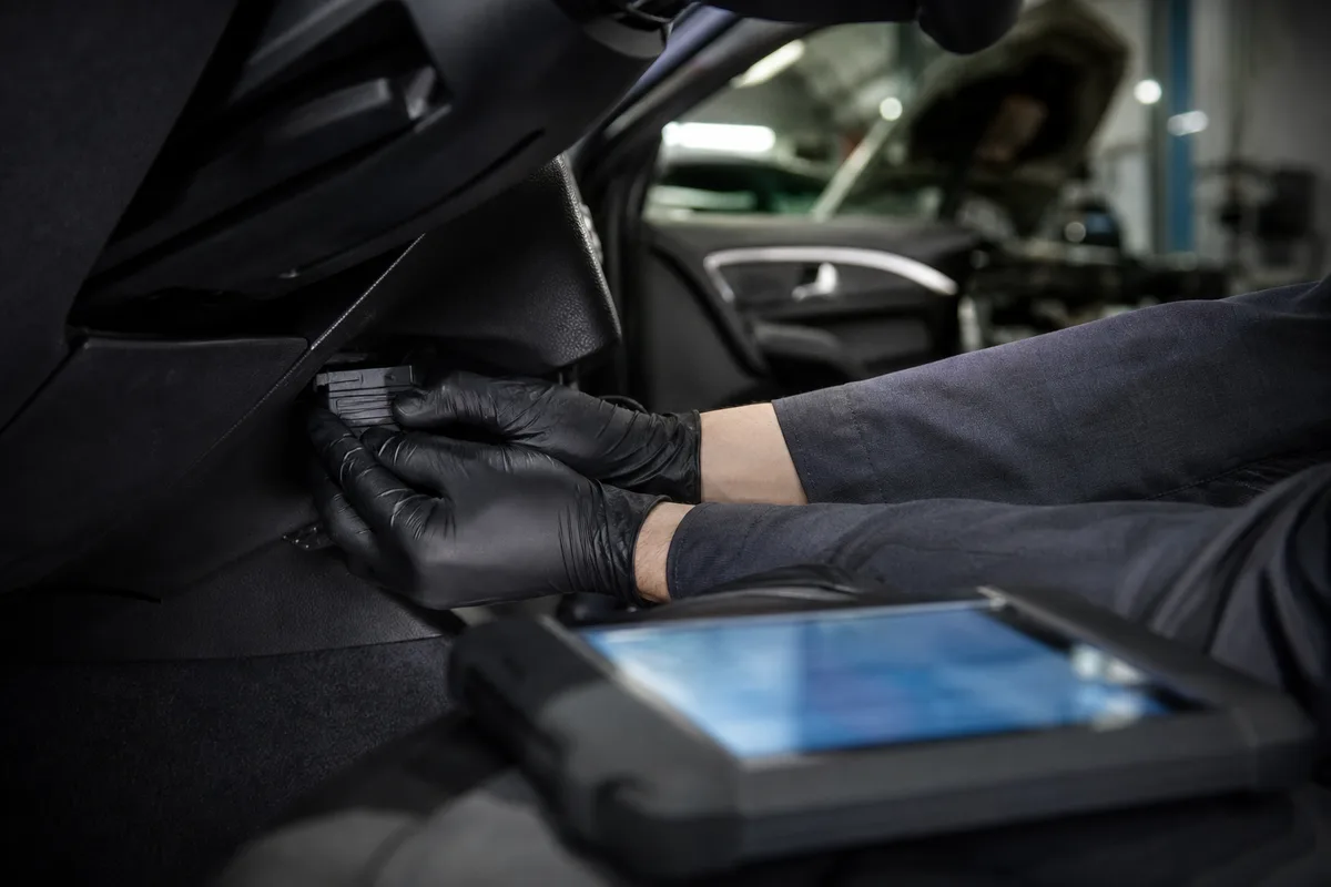 Mécanicien intervenant sur un moteur avec une valise de diagnostic électronique