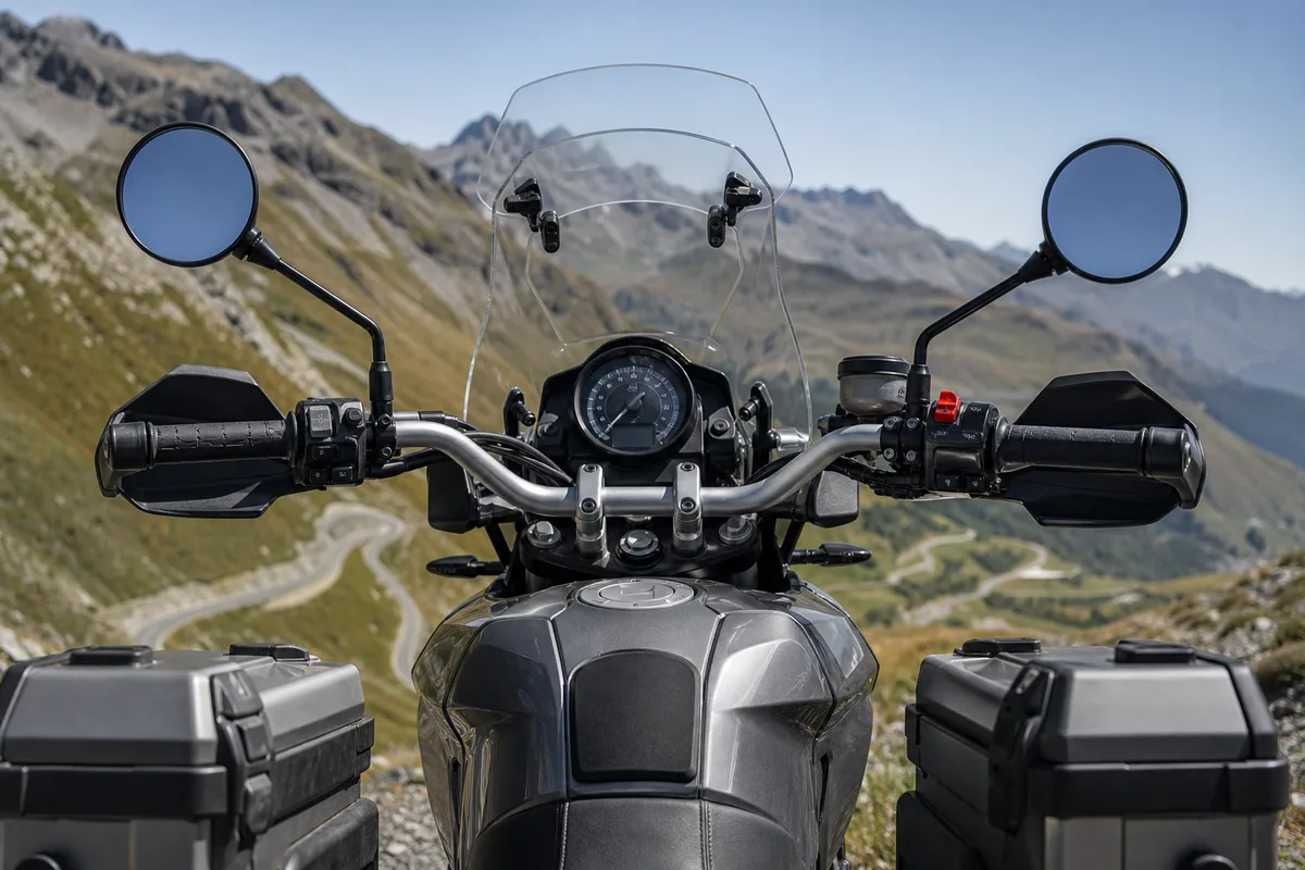 Cockpit d&rsquo;une moto trail équipée d&rsquo;un pare-brise et de sacoches rigides, vue de face sur un col de montagne